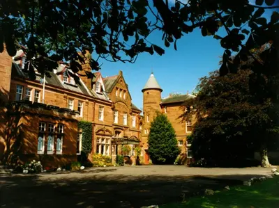 a large brick building with a tree in front of it at Savoy Park Hotel in Ayr