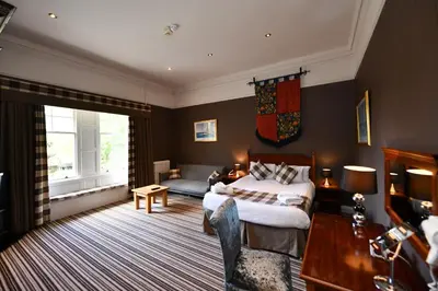 a bedroom with a bed and a couch and a table at Savoy Park Hotel in Ayr