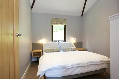 a bedroom with a bed with white sheets and a window at LOCH TAY HIGHLAND LODGES and GLAMPING PARK in Morenish