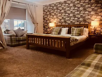 a bedroom with a bed and a couch and a stone wall at Creebridge House Hotel in Newton Stewart