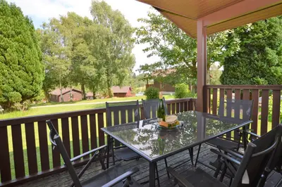 a patio with a table and chairs on a deck at Deer Croft Lodge in Hunters Quay