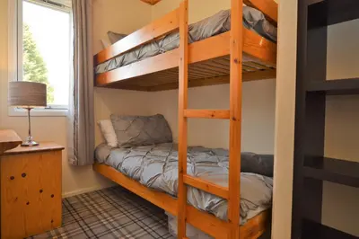 a bedroom with bunk beds in a room with a window at Deer Croft Lodge in Hunters Quay
