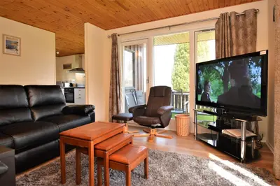 a living room with a couch and a flat screen tv at Deer Croft Lodge in Hunters Quay