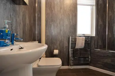a bathroom with a sink and a toilet and a window at Deer Croft Lodge in Hunters Quay