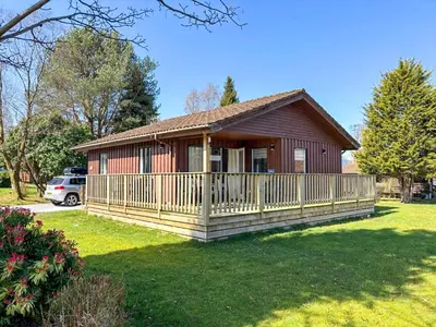 a small house with a porch and a yard at Deer Croft Lodge in Hunters Quay