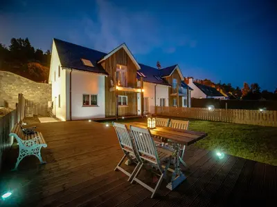a wooden deck with chairs and a wooden table at Taymore Lodge in Kenmore