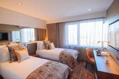 a hotel room with two beds and a desk at The Redhurst Hotel Glasgow in Giffnock