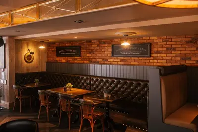 a dining room with tables and chairs and a brick wall at The Redhurst Hotel Glasgow in Giffnock