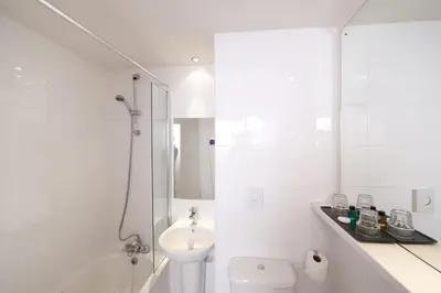 a white bathroom with a toilet and a sink at Leonardo Inn Glasgow West End in Glasgow