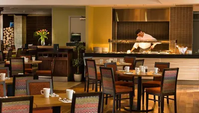 a restaurant with tables and a chef preparing food at Leonardo Inn Glasgow West End in Glasgow