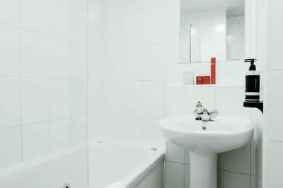a white bathroom with a sink and a bath tub at Muthu Queens Hotel, Oban in Oban