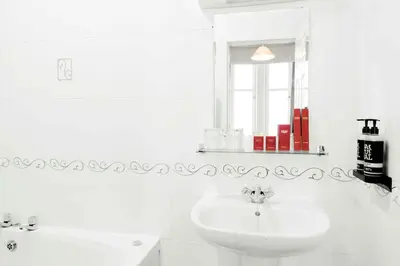a white bathroom with a sink and a window at Muthu Queens Hotel, Oban in Oban