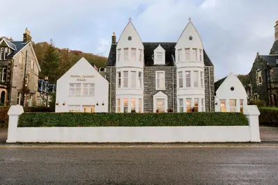 a large white house with a fence in front of it at Muthu Queens Hotel, Oban in Oban
