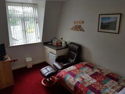 a bedroom with a bed and a chair and a desk at Balmoral Hotel in Moffat