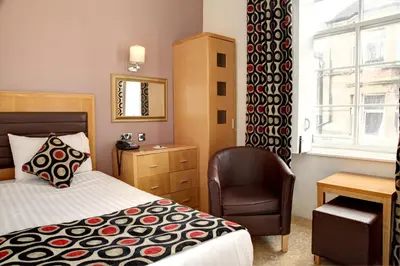 a bedroom with a bed and a chair and a window at Argyll Hotel in Dunoon