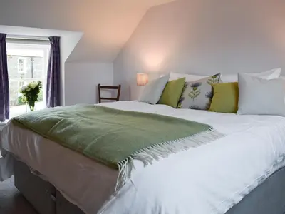 a bedroom with a large white bed with green pillows at Rowanlea in Muthill
