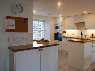 a kitchen with white cabinets and a clock on the wall at Rowanlea in Muthill