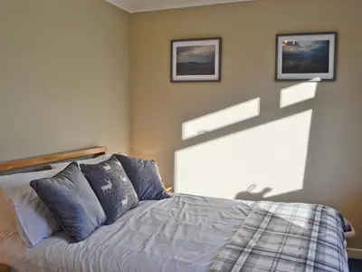 a bedroom with a bed and two pictures on the wall at Glencairn Rd in Langbank