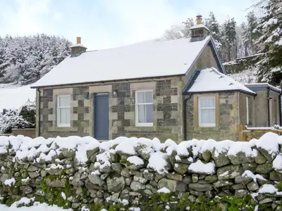 a stone cottage in the snow with a stone fence at Nettlebush Cottage-Uk5629 in Drummelzier