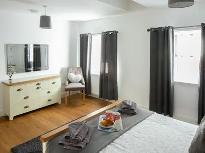a bedroom with a bed with a tray of food on it at Rossie Cottage in Auchterarder