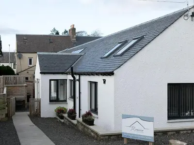 a white house with a sign in front of it at Rossie Cottage in Auchterarder