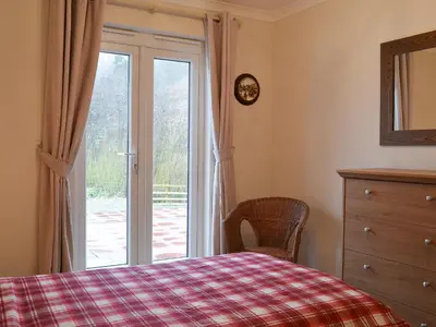 a bedroom with a bed and a sliding glass door at Riverside in Kilmelford