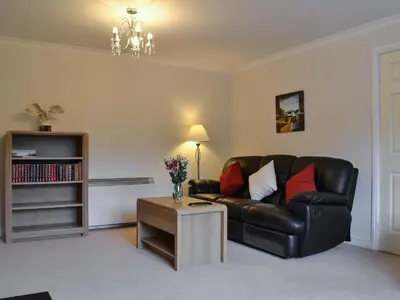 a living room with a black leather couch and a table at Riverside in Kilmelford