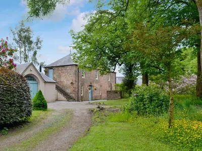 an old brick building with a driveway in front of it at The Old Stables in Sorn