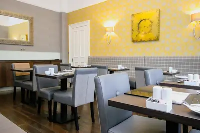 a restaurant with tables and chairs and a mirror at Embassy Apartments in Glasgow
