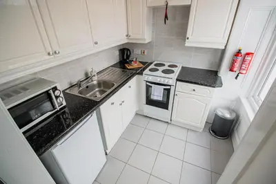 a small kitchen with white cabinets and a sink at Embassy Apartments in Glasgow