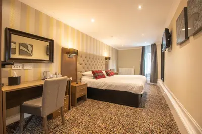 a bedroom with a bed and a desk and a chair at Embassy Apartments in Glasgow