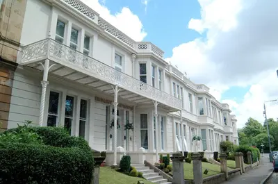 a white building with a balcony on the side of it at Embassy Apartments in Glasgow