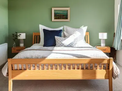 a bedroom with a large bed with blue and white pillows at Strathcashel Cottage in Rowardennan