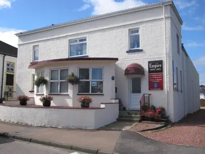 a white building with flowers in front of it at Empire Travel Lodge in Lochgilphead