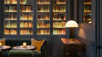 a library with a green couch and tables and books at JA Mar Hall Scotland in Bishopton