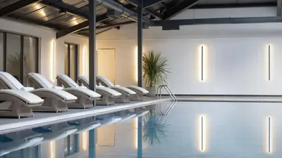 a swimming pool with white chairs next to a swimming pool at JA Mar Hall Scotland in Bishopton