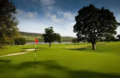 a golf course with a red flag on the green at JA Mar Hall Scotland in Bishopton
