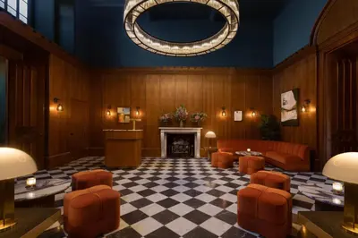 a waiting room with a fireplace and orange chairs at JA Mar Hall Scotland in Bishopton