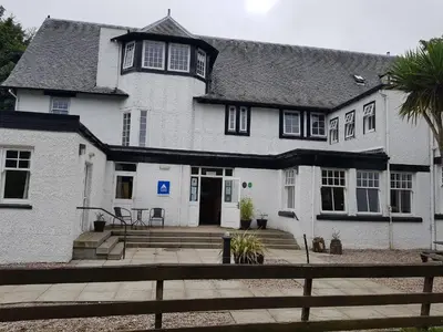 a white house with a fence in front of it at Lochranza Youth Hostel in Lochranza