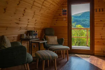 a room with chairs and a window in a log cabin at Glencoe Youth Hostel in Ballachulish
