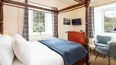 a bedroom with a canopy bed and a chair at Killin Hotel in Killin