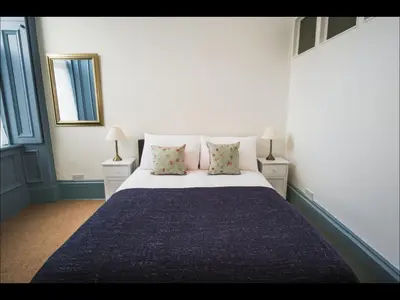 a bedroom with a large bed with two tables and a mirror at Cedar Apartment in Helensburgh