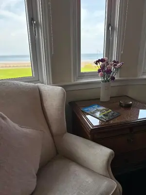 a living room with a chair and a table with flowers at Beaches in Ayr