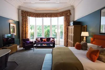 a bedroom with a large window and a bed and a couch at One Devonshire Gardens a Hotel Du Vin in Glasgow