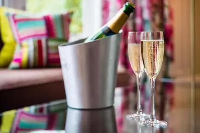 a bottle of champagne in a bucket next to two glasses at One Devonshire Gardens a Hotel Du Vin in Glasgow