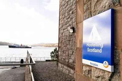 a sign on a building next to a body of water at Oban Youth Hostel in Oban