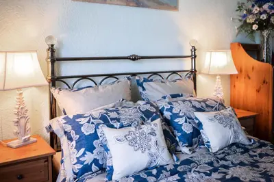 a bed with blue and white pillows and two lamps at Drumfearne Guesthouse & Tearoom in Carradale