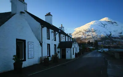 a building with a mountain in the background at Inn at Ardgour in Onich