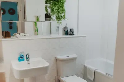 a white bathroom with a toilet and a sink at Lovely Bohemian Apartment in Heart of City Life in Glasgow