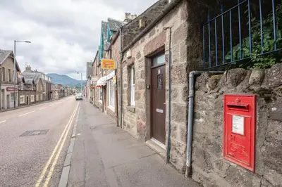 a red box on the side of a stone building on a street at Socair in Callander